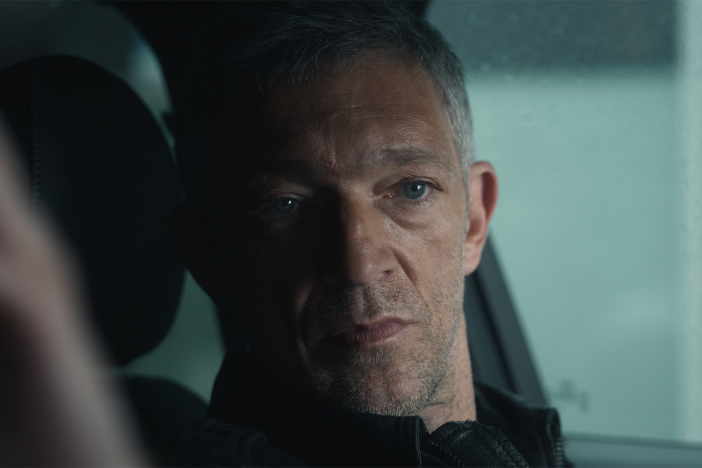 Vincent Cassel está sentado em um carro em Liaison.