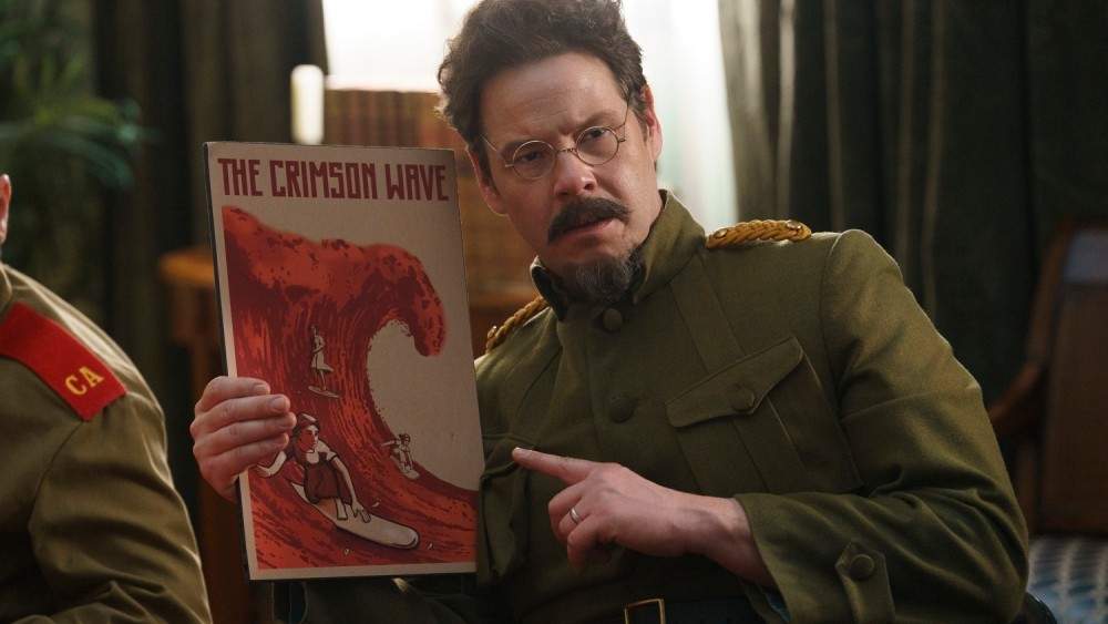 A Soviet dictator points to a poster labeled "The Crimson Wave."