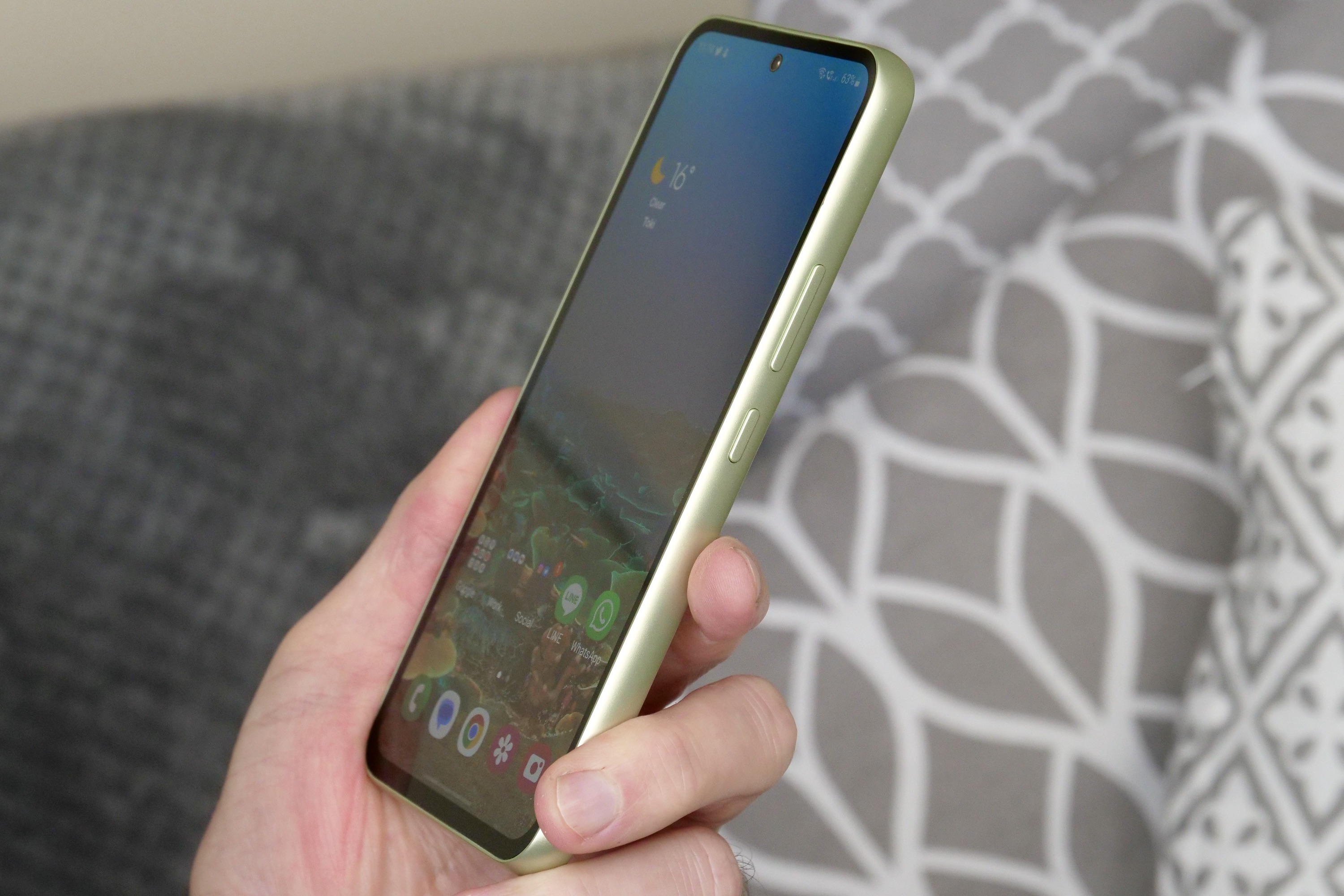 A person holding the Samsung Galaxy A54, seen from the side.