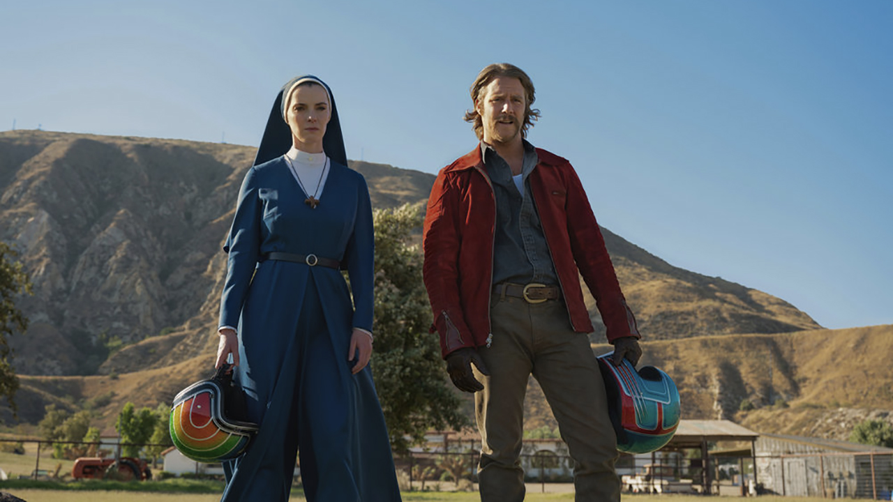 Simone and Wiley stand on a cliff holding up Mrs. Davis' motorcycle helmet.