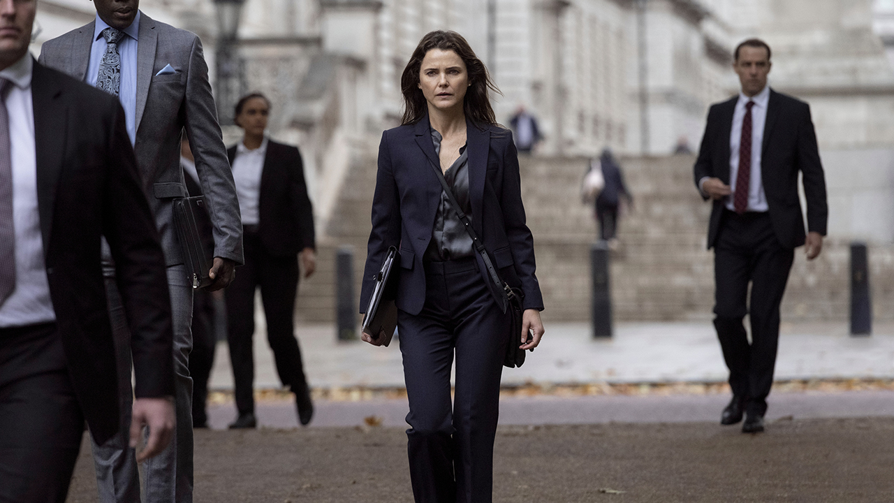 Keri Russell Walking in the street wearing a black suit in a scene from The Diplomat.