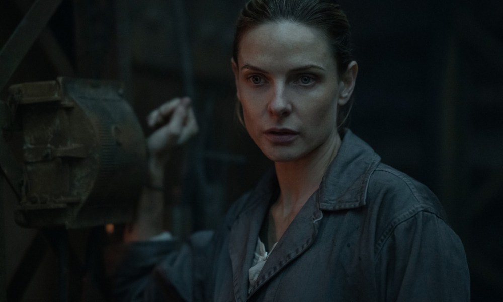 Rebecca Ferguson holds onto a mechanical lever in Silo.