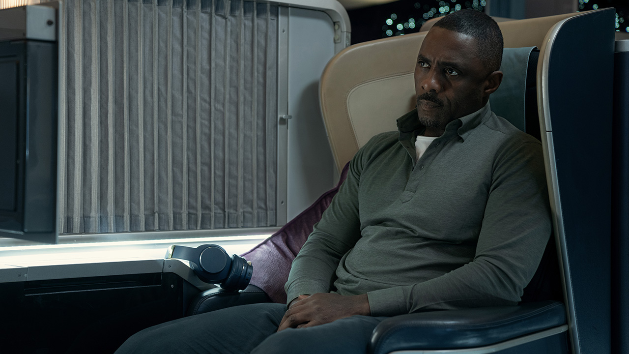 Idris Elba as Sam sitting on a plane seat in a scene from Hijack on Apple TV+.