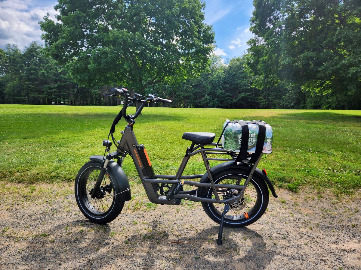 Rad Power Bikes RadRunner 3 Plus con una caja de botellas de agua atada al portabultos trasero.