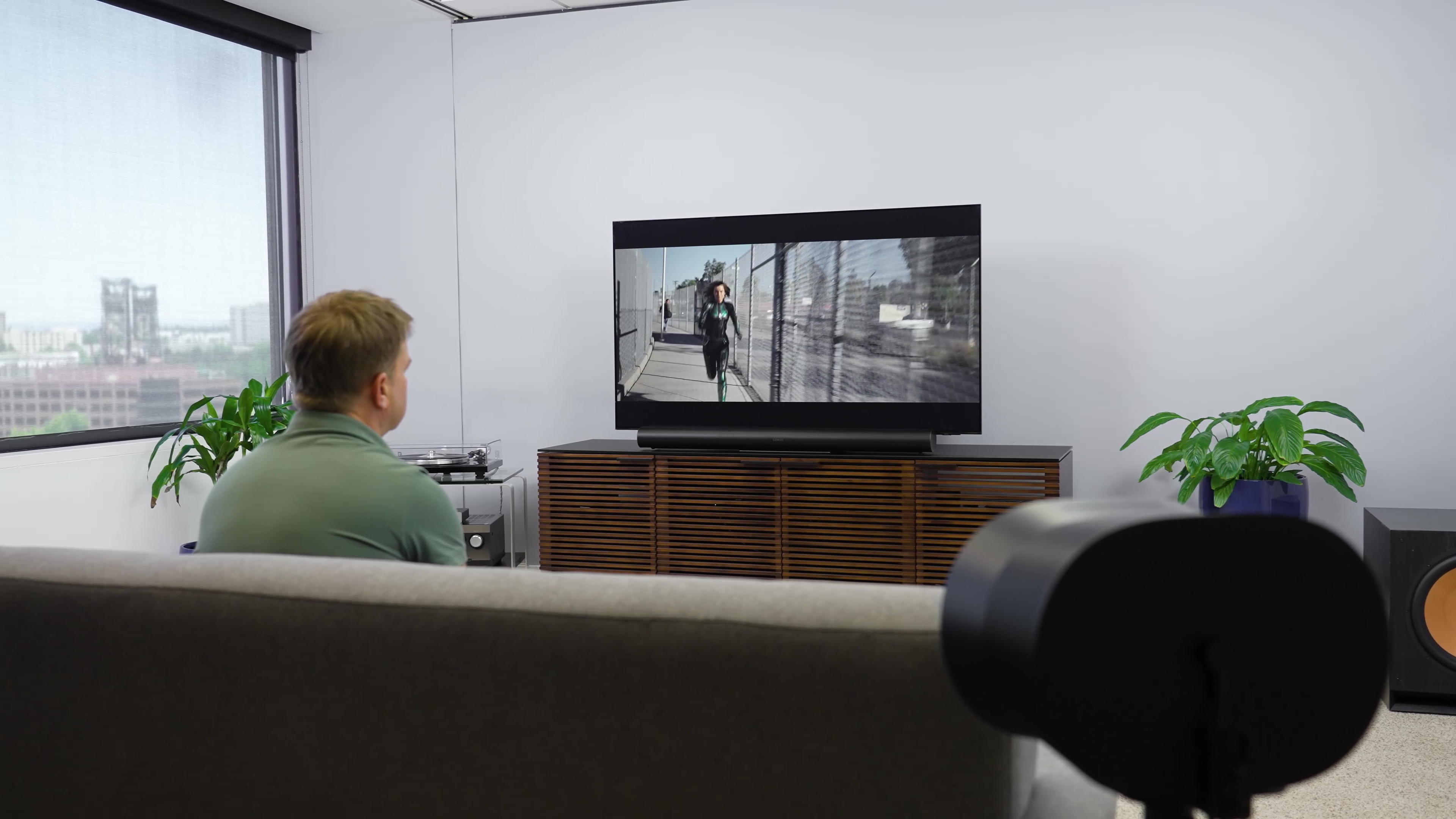 Un hombre mira una película en un estudio con un Sonos Era 300 en una configuración de sonido envolvente.