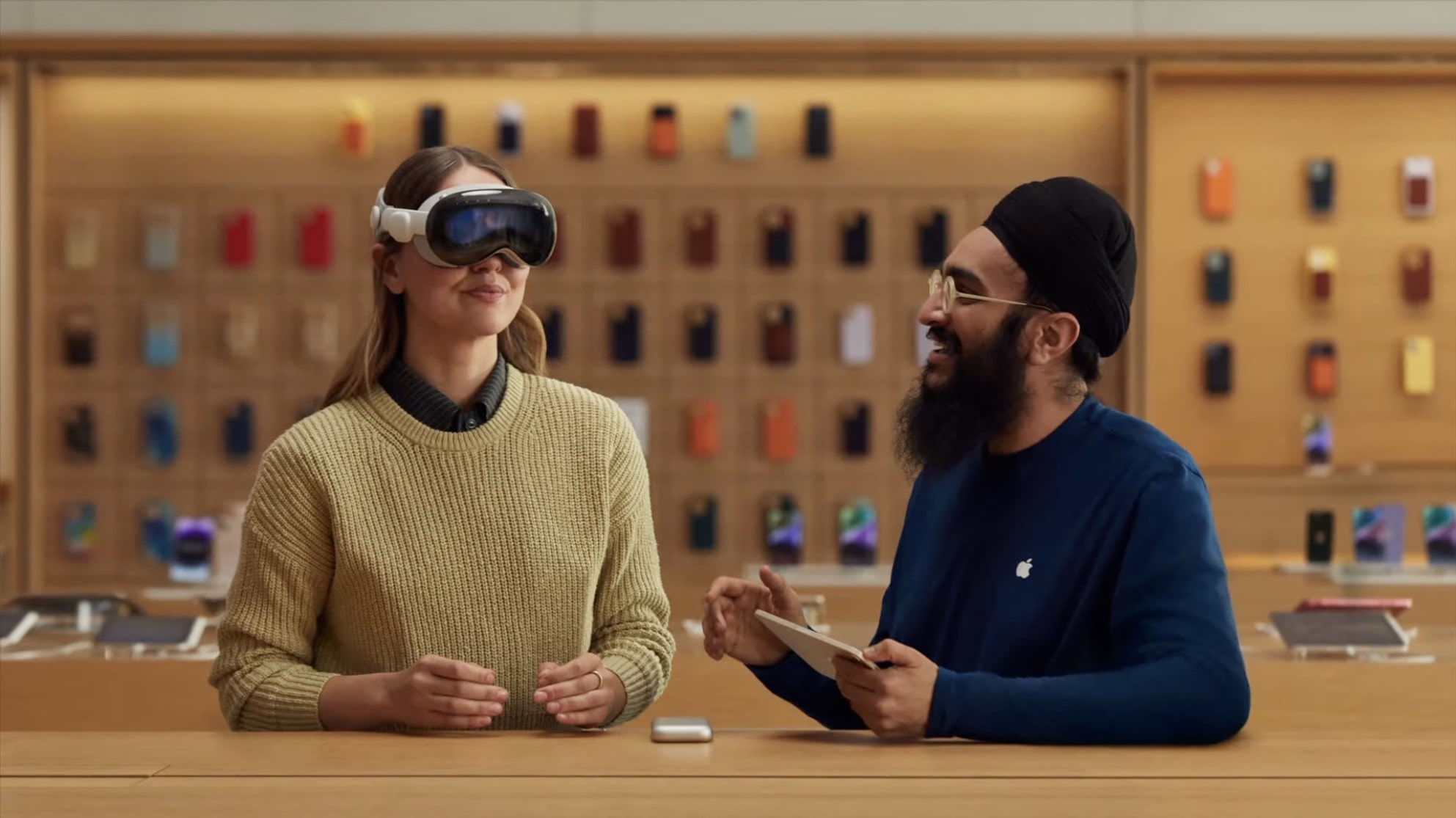 Человек примеряет гарнитуру смешанной реальности Apple Vision Pro в Apple Store вместе с сотрудником Apple.