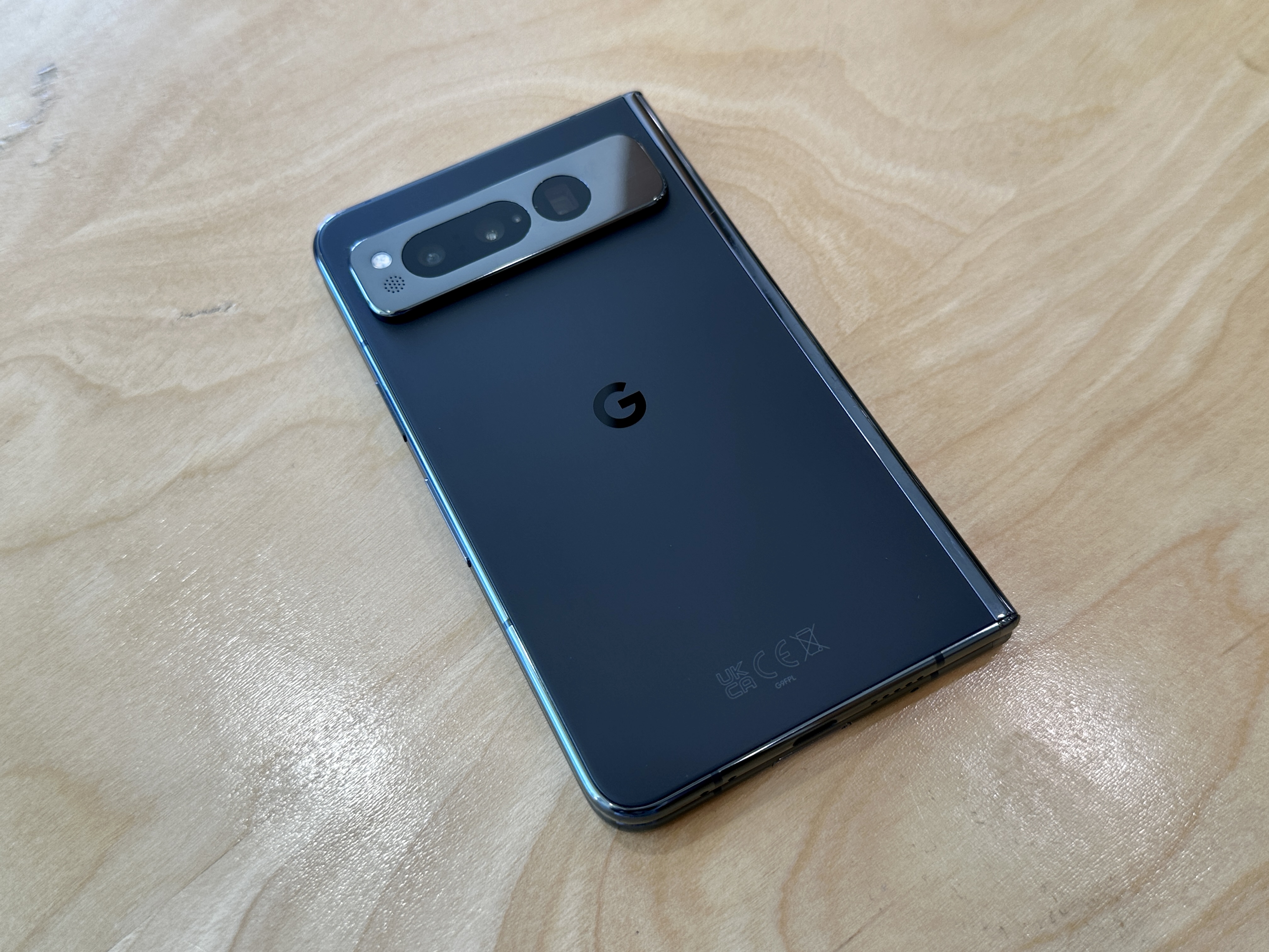 Google Pixel Fold en obsidiana sobre una mesa de madera clara.