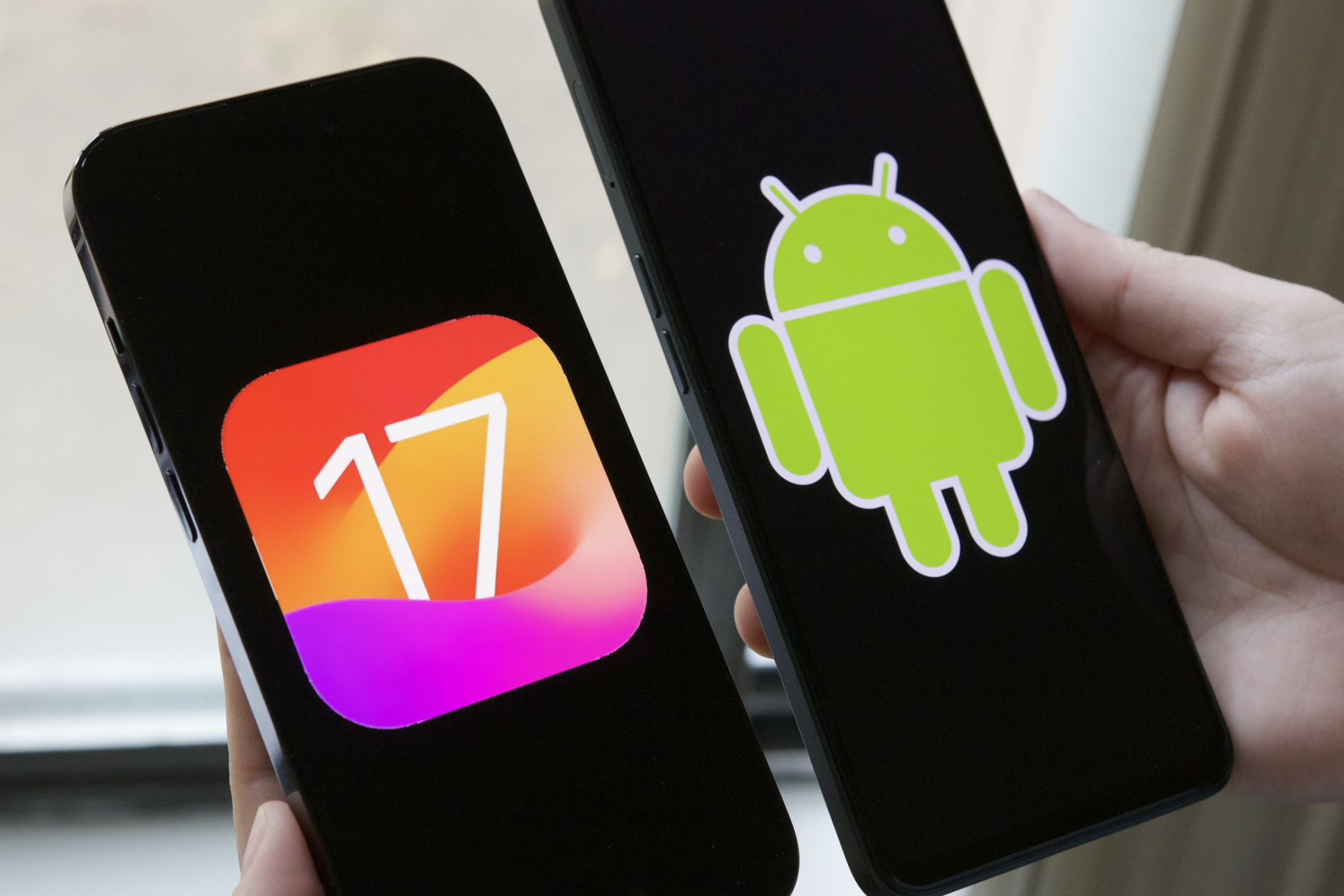 iOS 17-Logo auf einem iPhone, Android-Logo auf einem Android-Telefon.