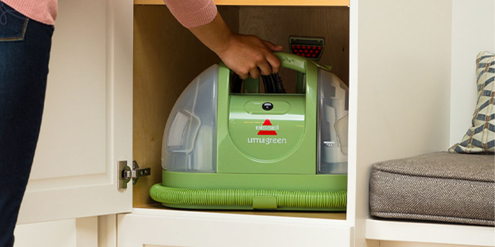 Der tragbare Mehrzweck-Teppich- und Polsterreiniger von Bissell Little Green wird in einen Schrank gestellt.