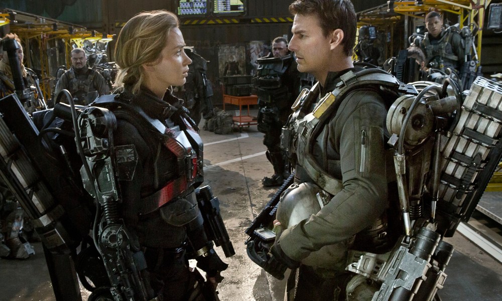 Emily Blunt and Tom Cruise face each other while wearing mech suits in Edge of Tomorrow.