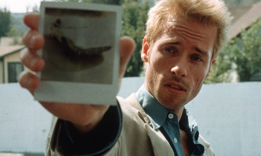 Guy Pearce as Leonard Shelby showing a polaroid to the camera in Memento.