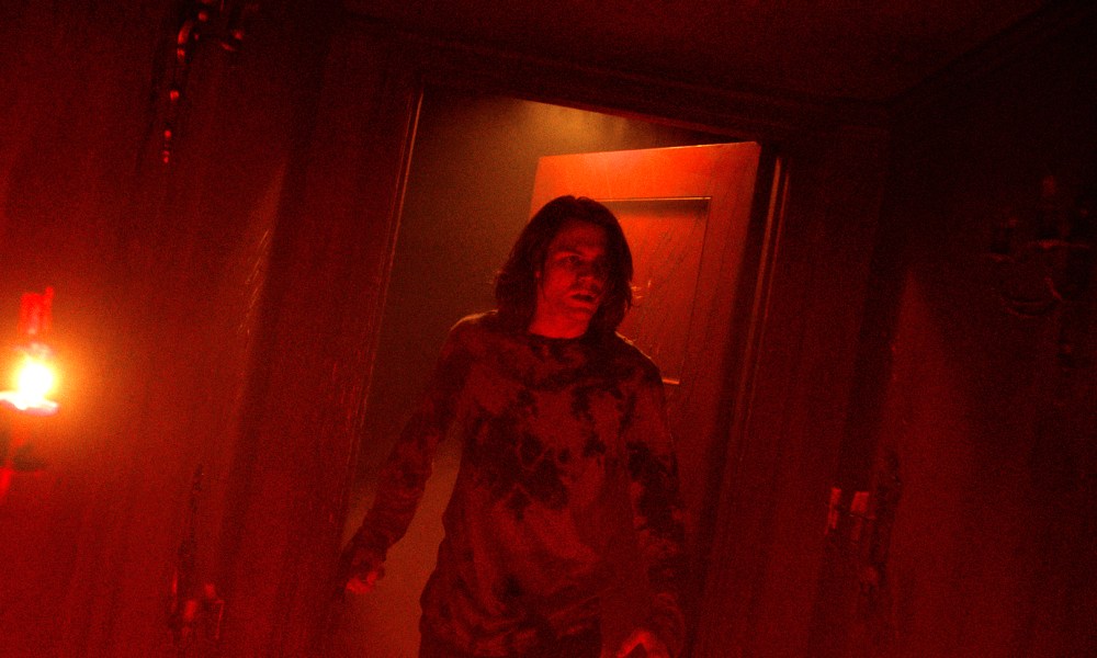 Ty Simpkins stands in a red doorway in Insidious: The Red Door.