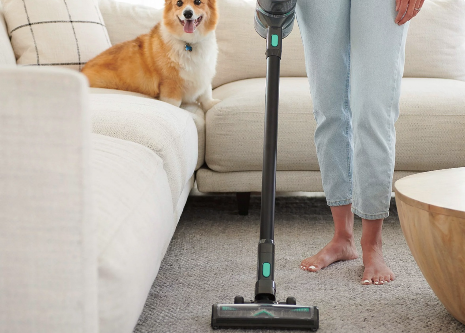 A woman vacuums her living room with a Wyze cordless stick vacuum.