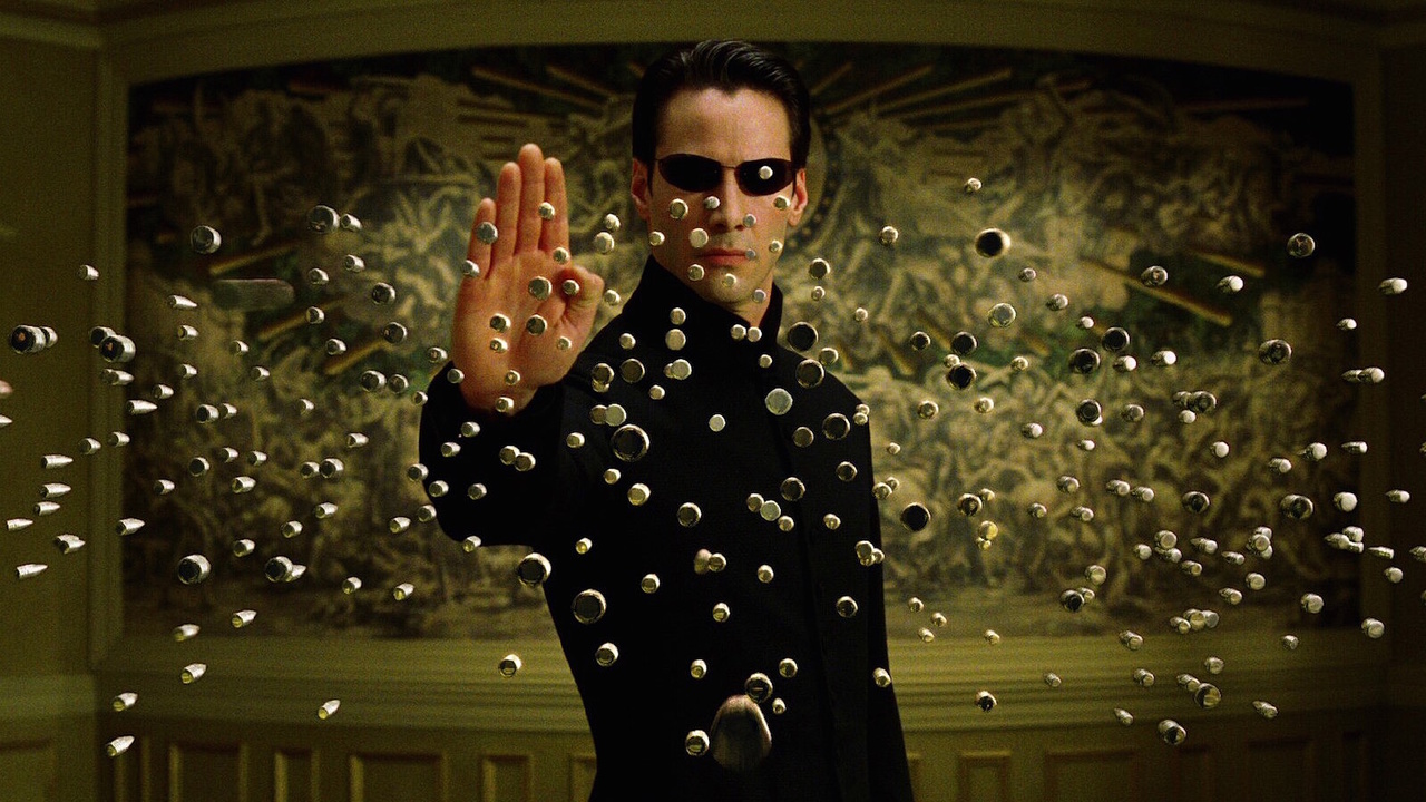 Keanu Reeves como Neo deteniendo docenas de balas que se aproximan en The Matrix Reloaded.