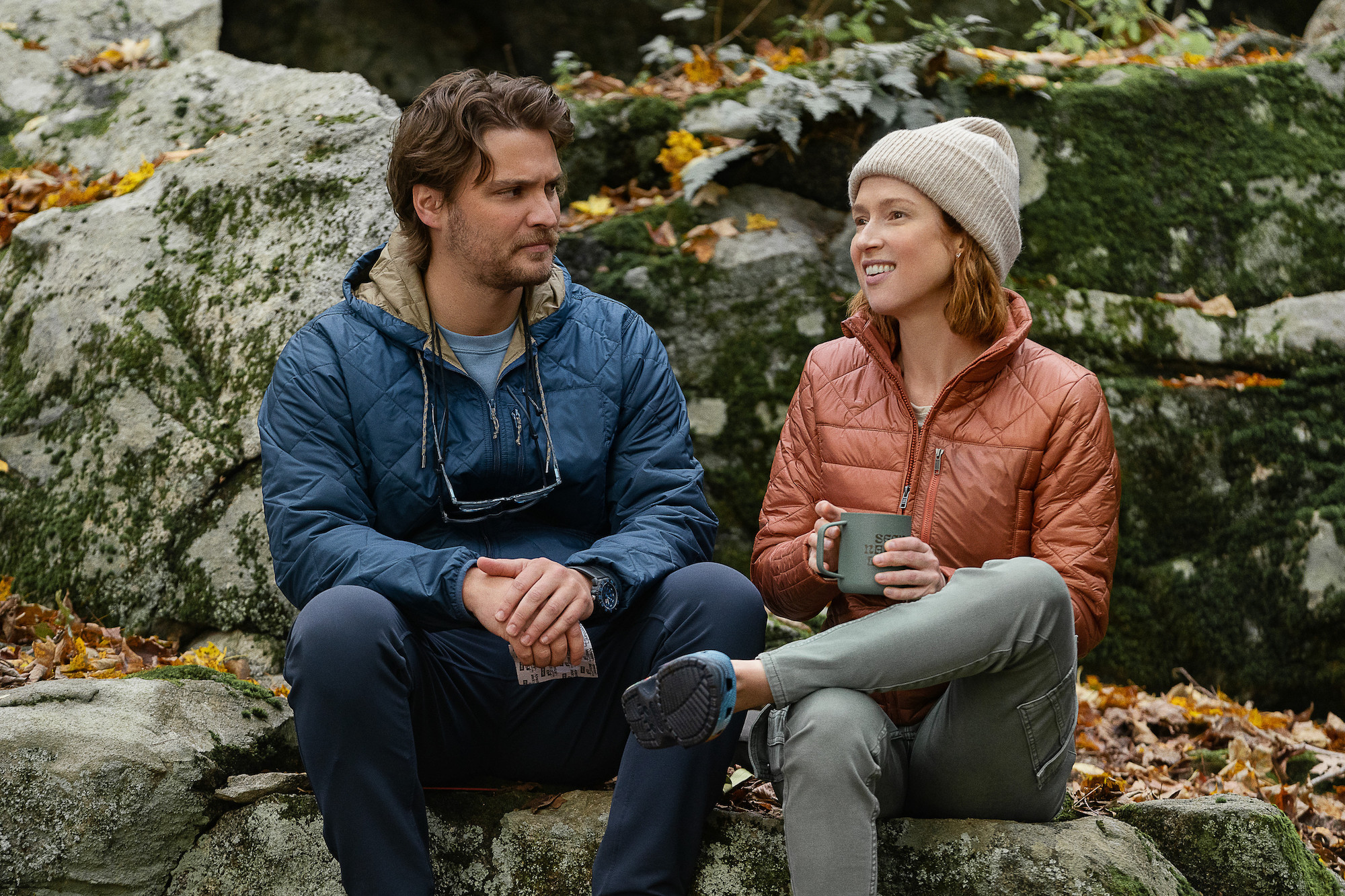 A young couple sits next to each other on rocks in Happiness for Beginners.