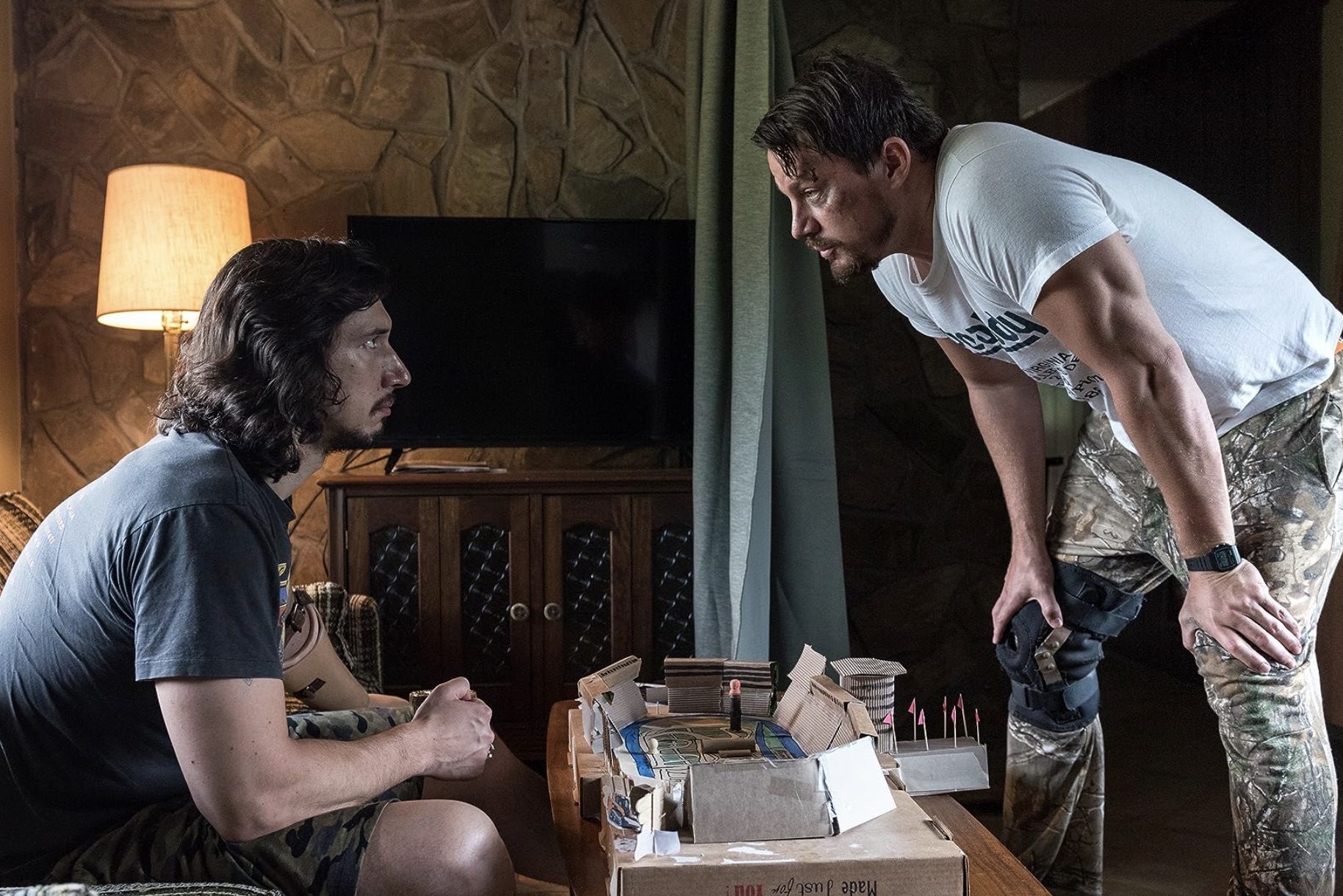 Adam Driver sits on the bench while Channing Tatum stands above him in Logan Lucky.