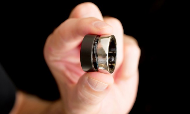 A person holding the Ultrahuman Ring Air and the Oura Ring.