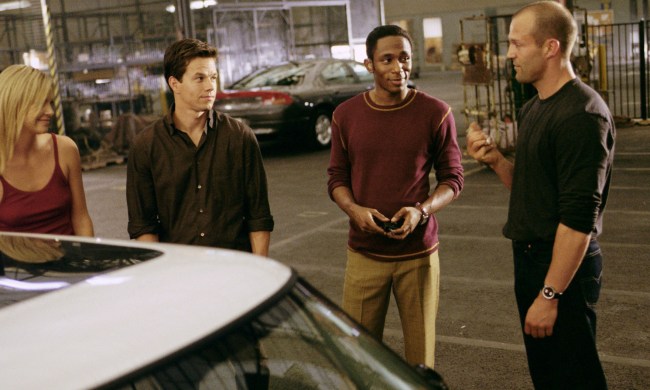 Four people stand around a car in The Italian Job.