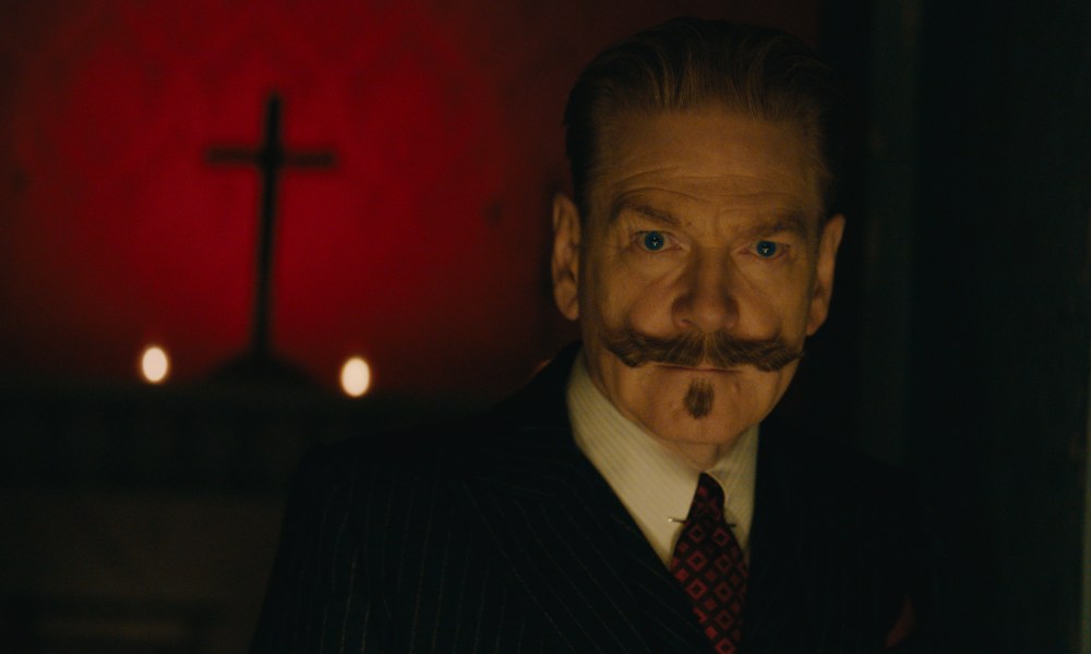 Hercule Poirot stands near a cross in A Haunting in Venice.