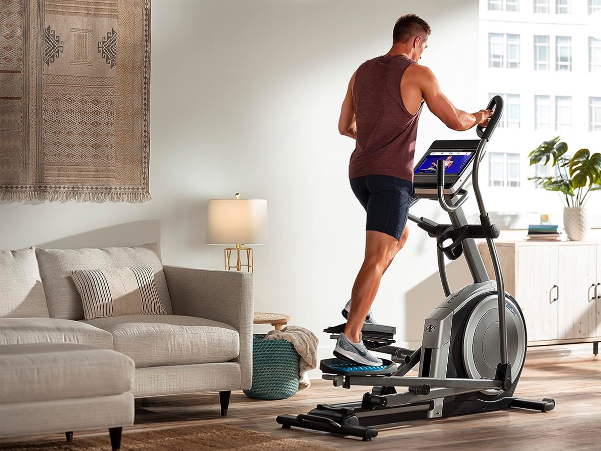 A man works out on the NordicTrack commercial smart elliptical in his apartment.