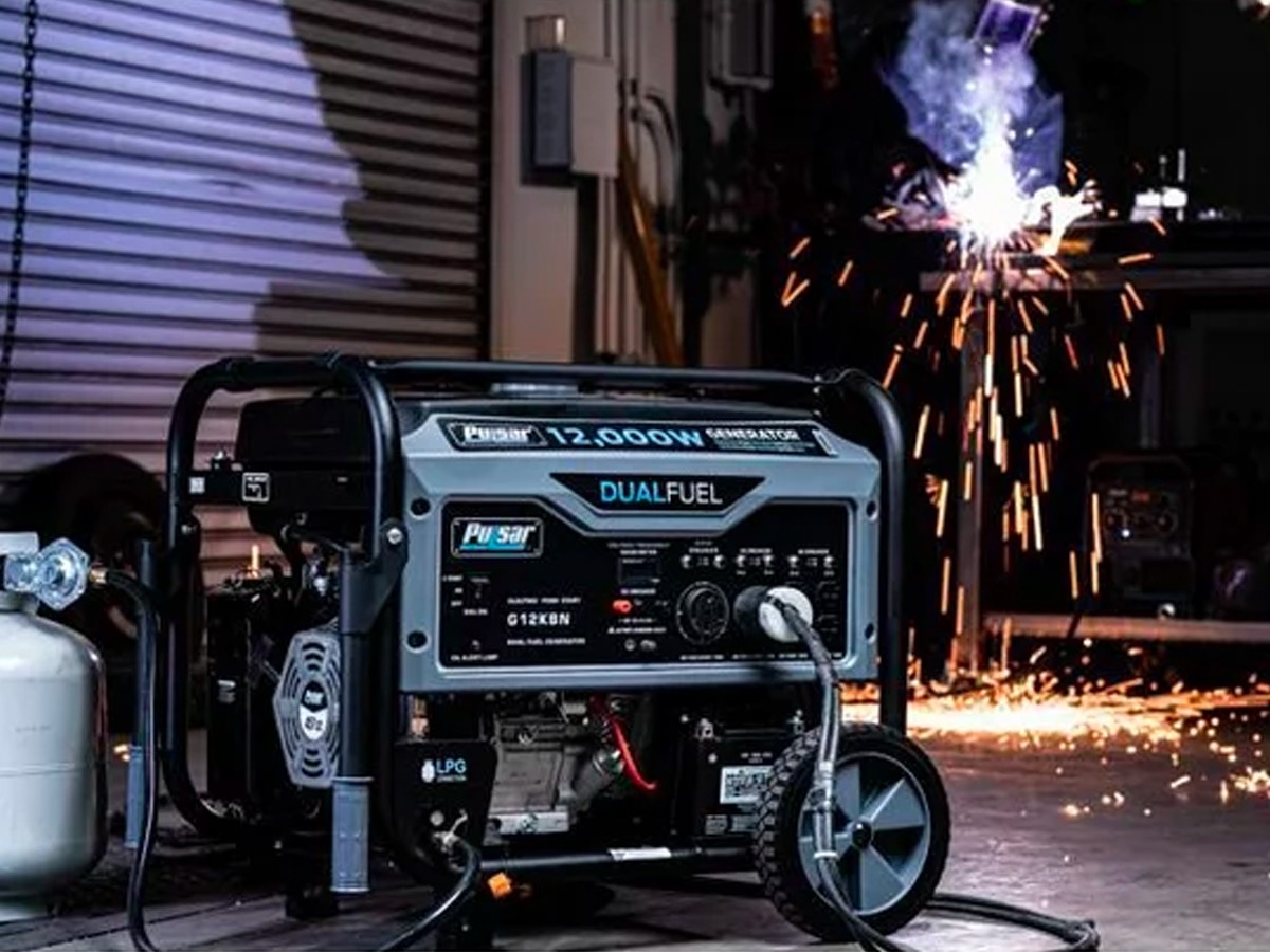 The Pulsar 12,000W Dual Fuel Portable Generator in Space Gray with Electric Start on a work site.