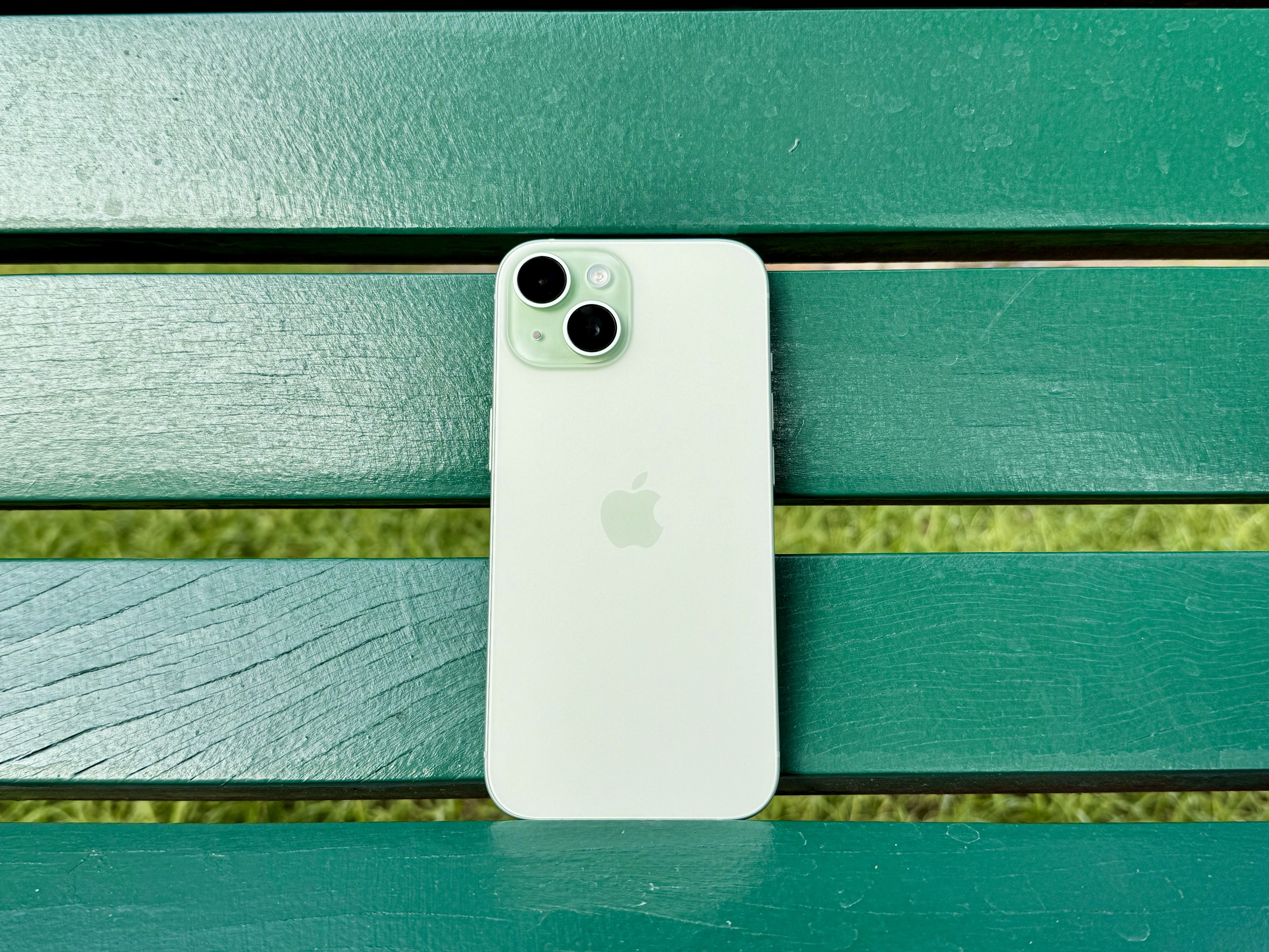 Un iPhone 15 vert sur un banc vert.