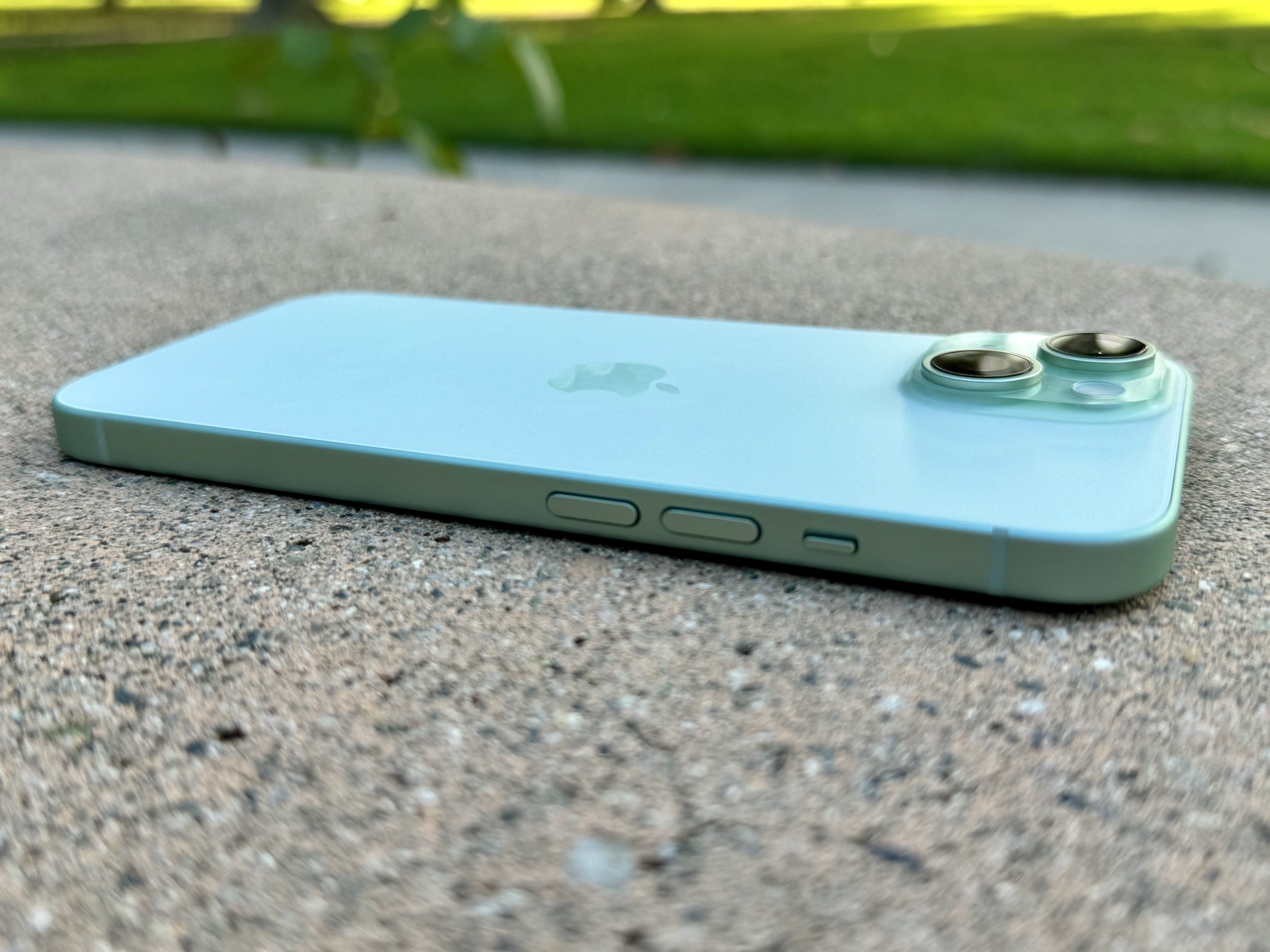 Side view of green iPhone 15 laying flat.