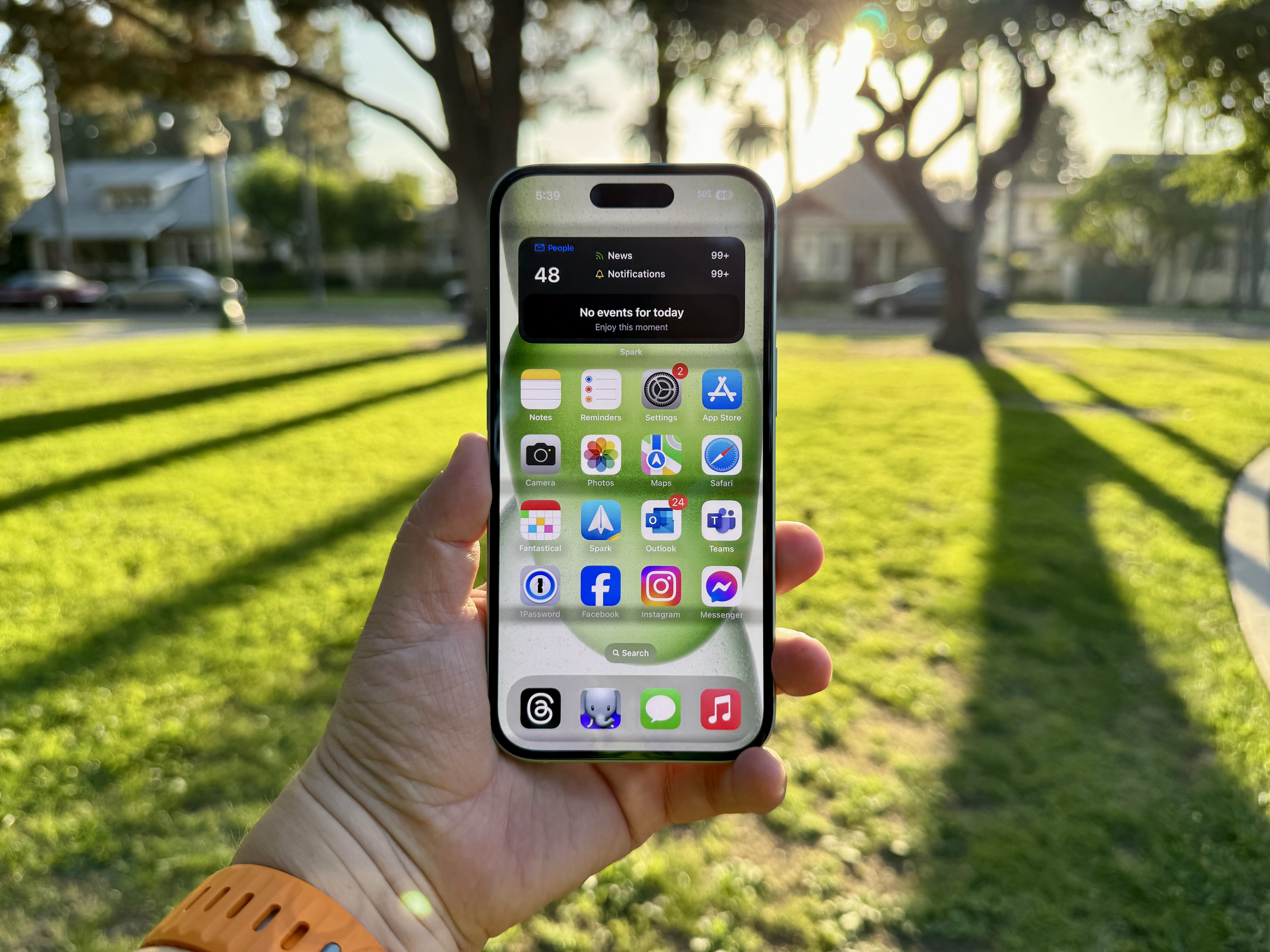 Un iPhone 15 vert en main affichant l'écran d'accueil.