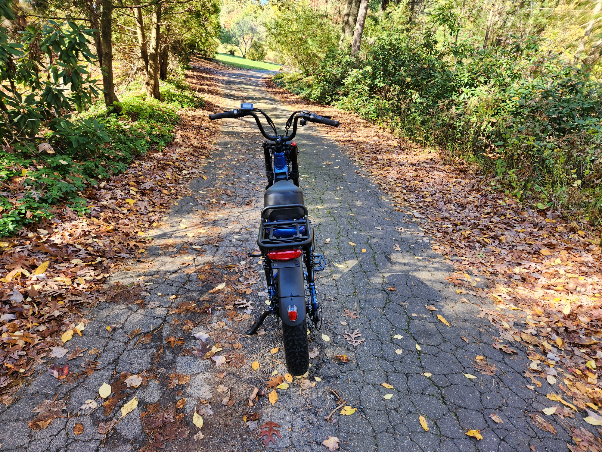 Juiced Bikes Scorpion X2 von hinten gesehen, geparkt mitten auf einem gepflasterten Feldweg.