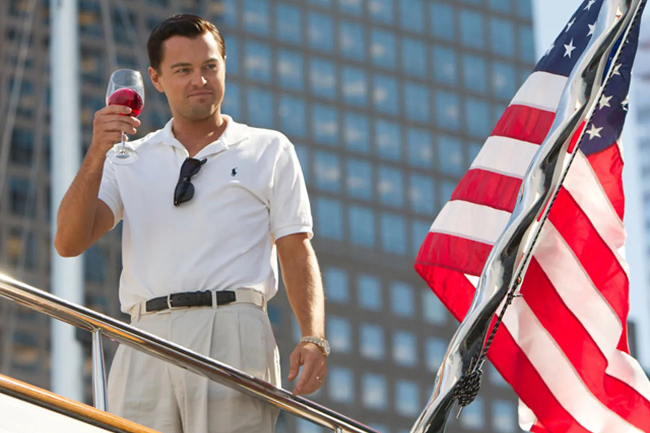 Leonardo DiCaprio está perto de uma bandeira americana em O Lobo de Wall Street.