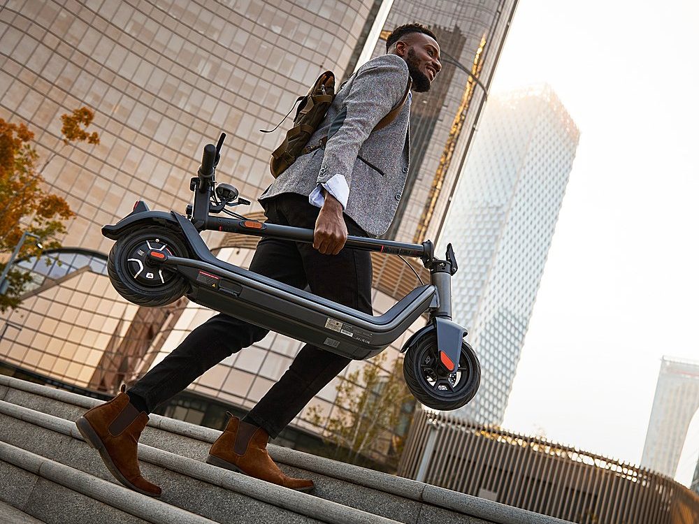 A man carrying the easily foldable NIU KQi3 Pro up stairs on the way to work.