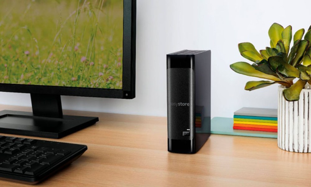 The WD Easystore 14TB External USB 3.0 hard drive on a desk next to a monitor and near a plant.