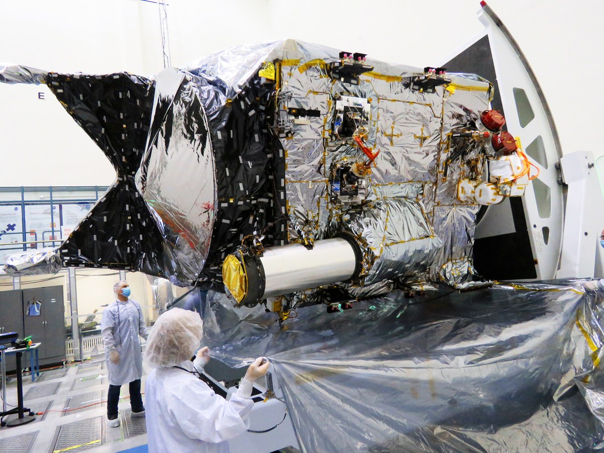 Der Flugtransceiver für die Demonstration der Deep Space Optical Communications-Technologie der NASA ist an seinem großen röhrenförmigen Sonnenschirm auf der Raumsonde Psyche zu erkennen, der hier in einem Reinraum im Jet Propulsion Laboratory der NASA in Südkalifornien zu sehen ist.