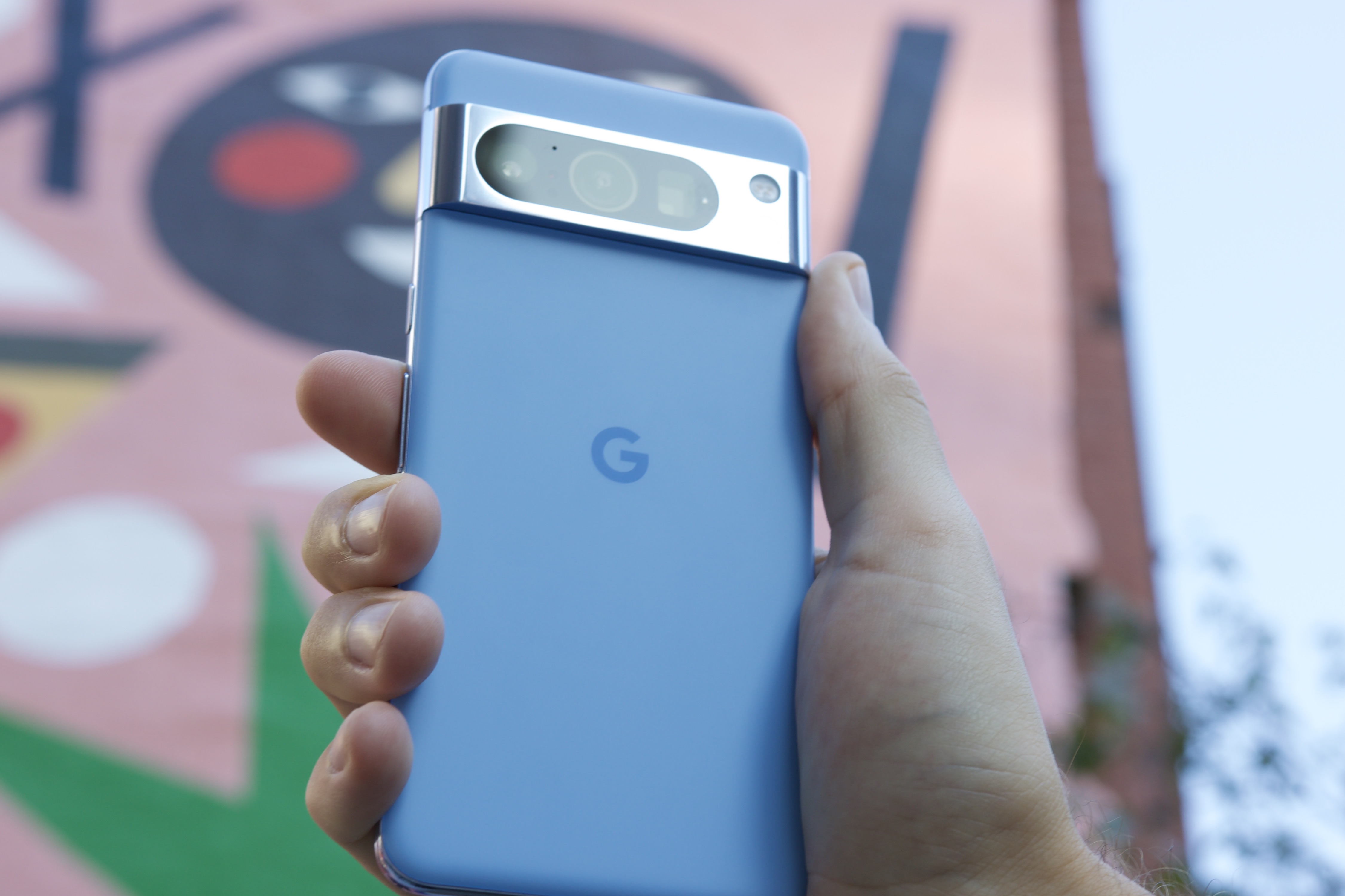 नीले Google Pixel 8 Pro को सूरज के सामने पकड़े हुए।