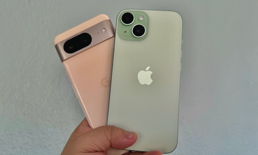 A rose Google Pixel 8 (left) held in hand with a green iPhone 15.