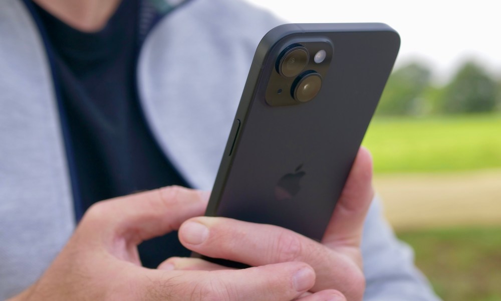 A person holding the Apple iPhone 15 Plus, showing the camera.