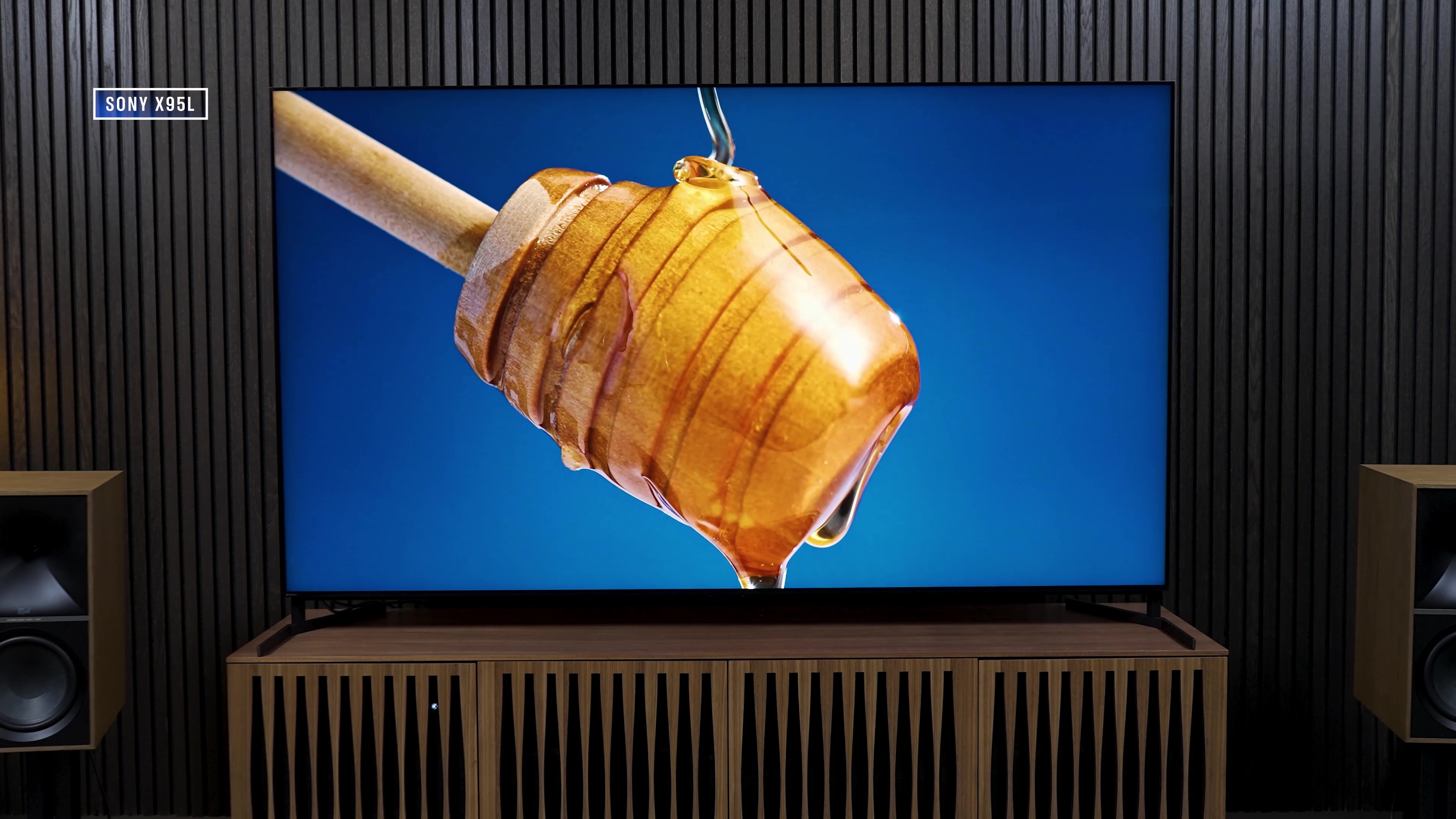 Honey being drizzled from a honey dripper displayed on a Sony X95L.