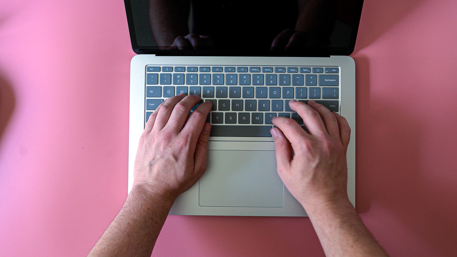 Overhead view of someone typing on a surface laptop.