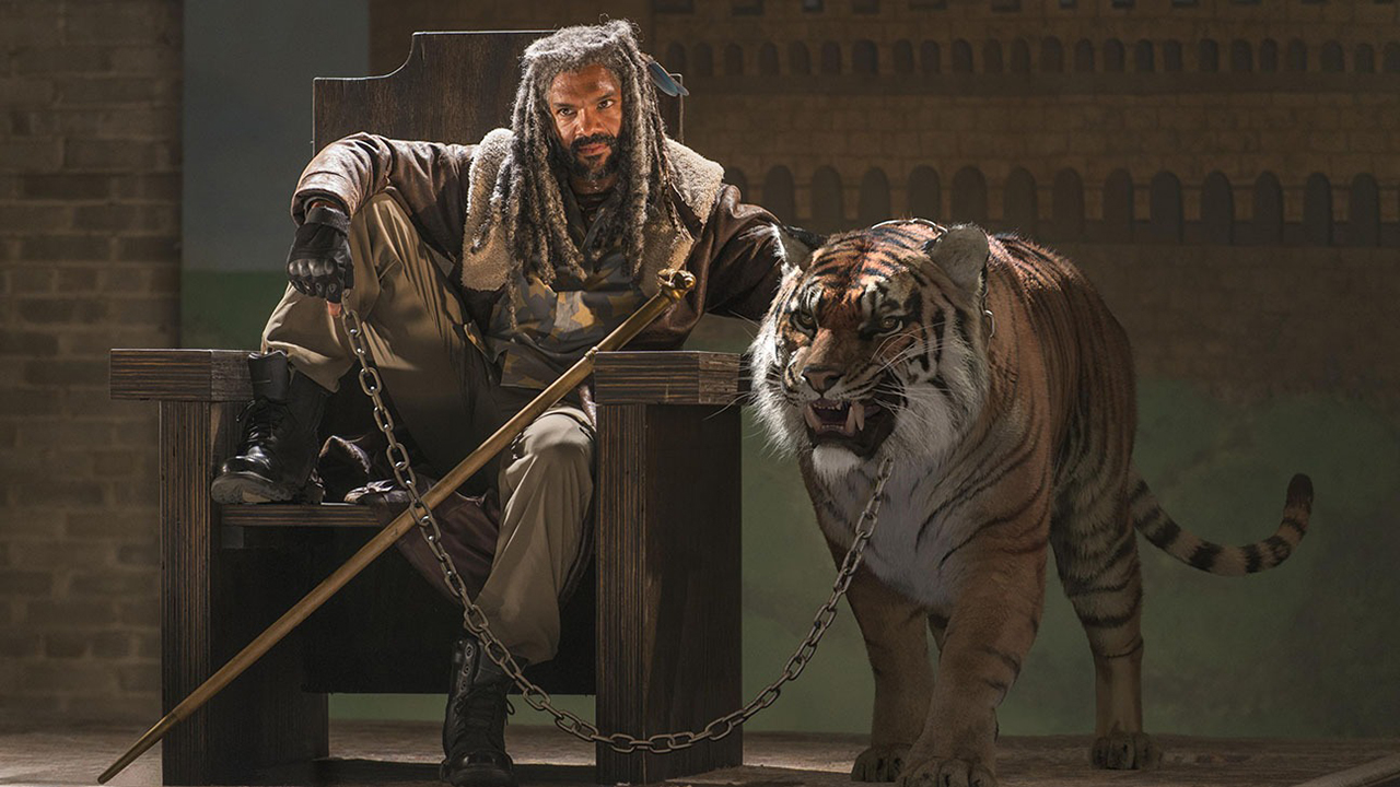 Ezekiel de The Walking Dead sentado em seu trono, com a perna em pé com Shiva, o tigre, ao lado dele.