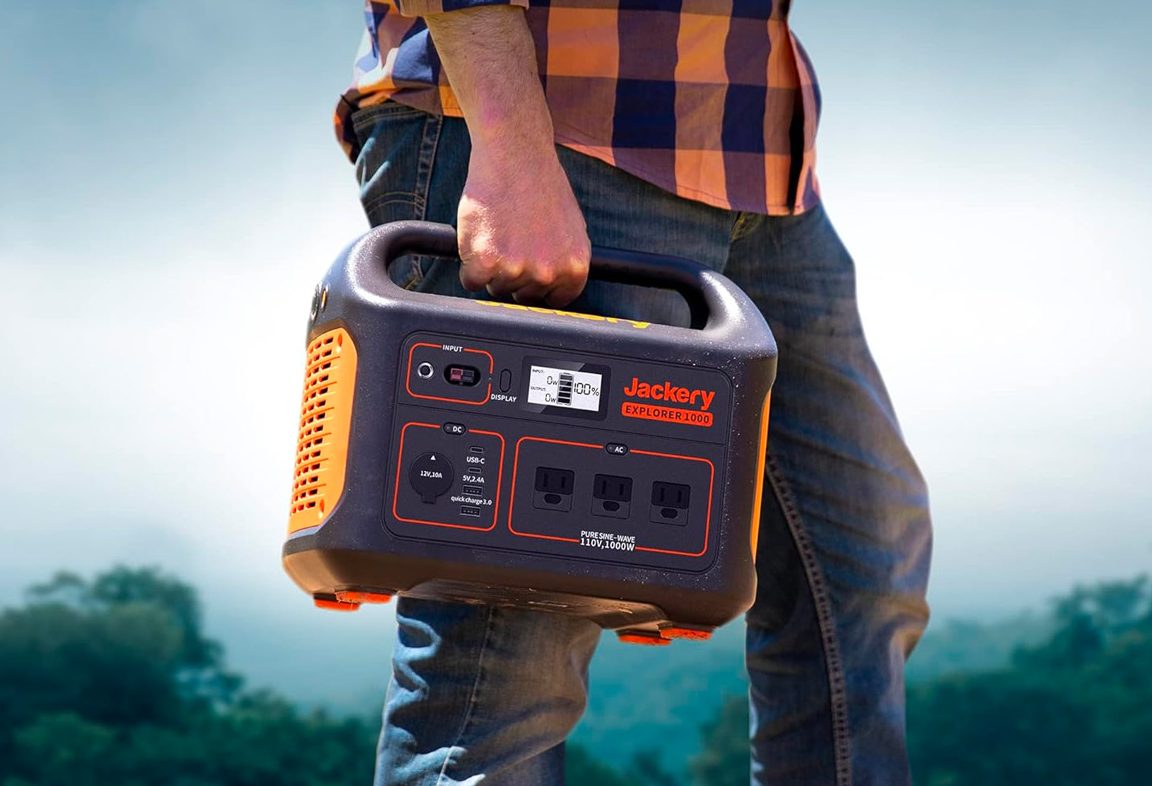 Un homme porte la centrale électrique portable Jackery Explorer 1000 avec des arbres en arrière-plan.