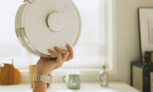 A person holding the SwitchBot K10+ robot vacuum.