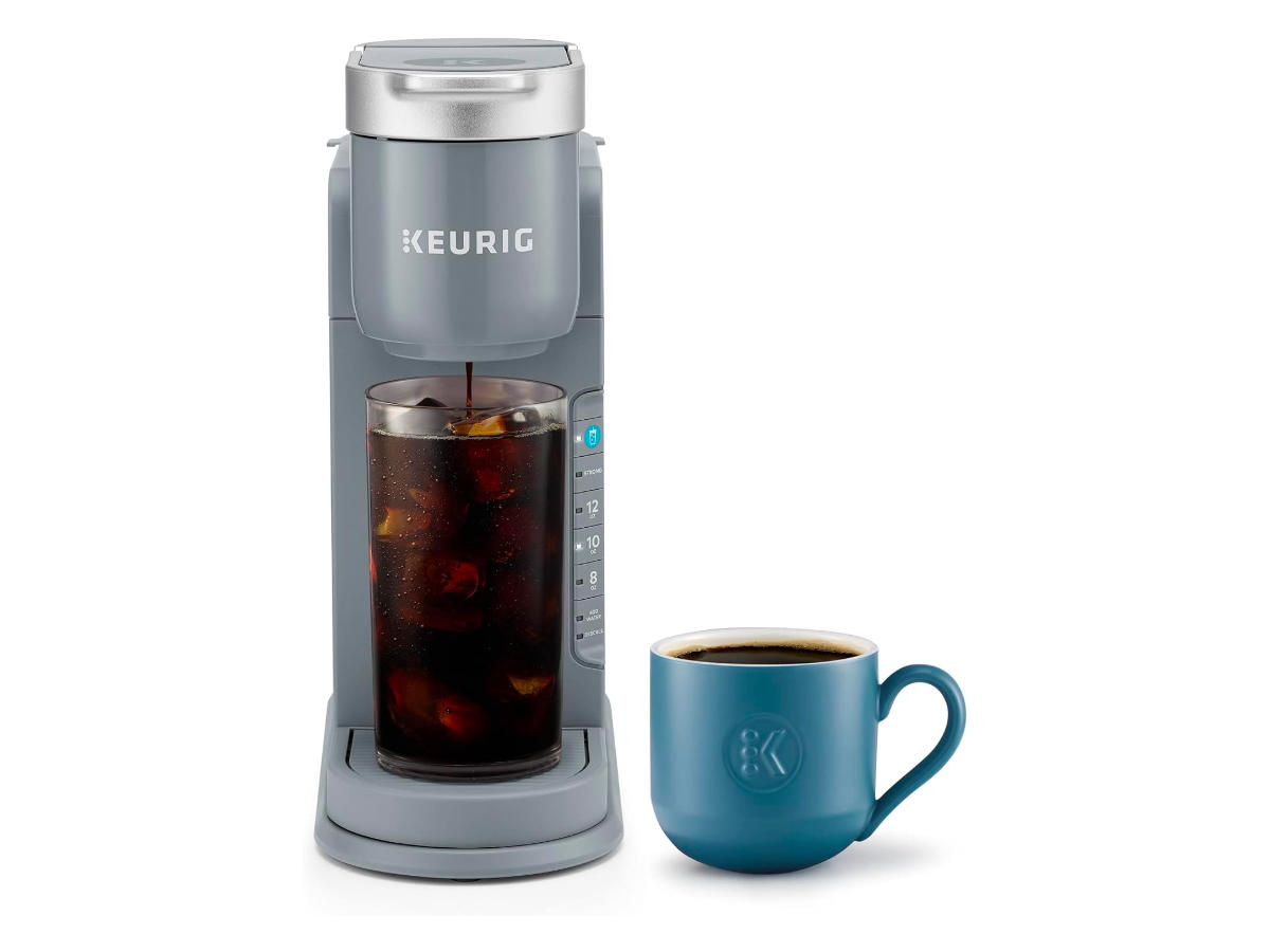 A cafeteira Keurig K-Iced ao lado de uma caneca contra um fundo branco.