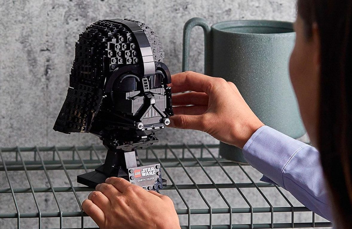 Une femme pose le casque Lego Star Wars Dart Vader sur une étagère.