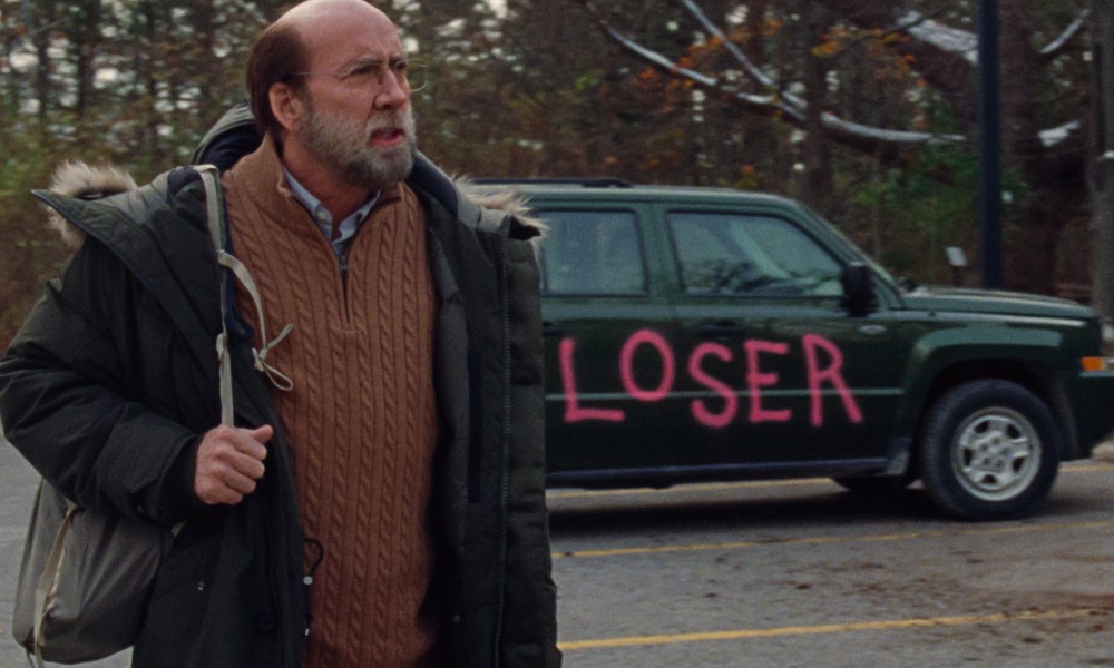 Nicolas Cage stands near a spray-painted car in Dream Scenario.