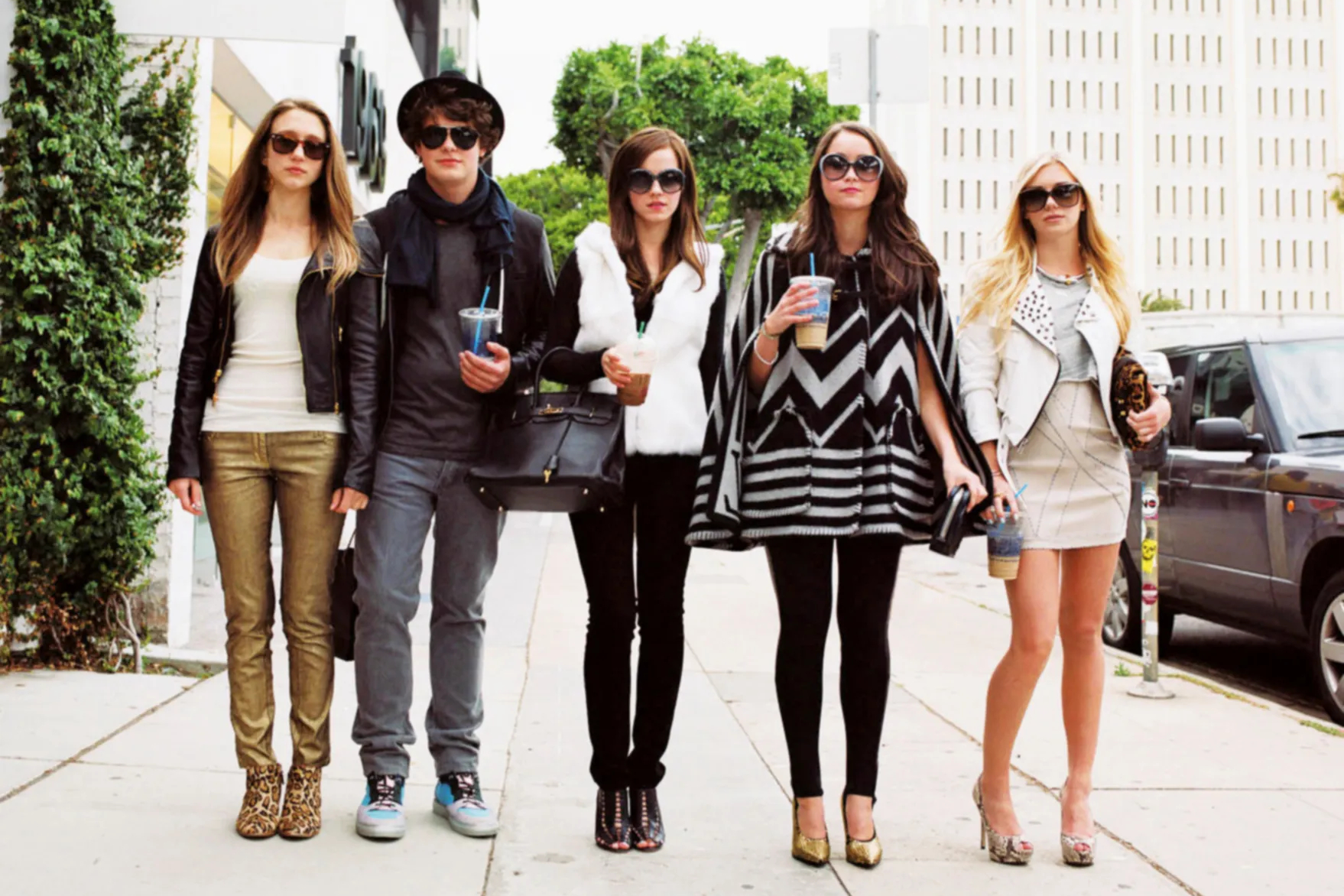 Os membros do elenco do Bling Ring usam óculos escuros e caminham juntos.