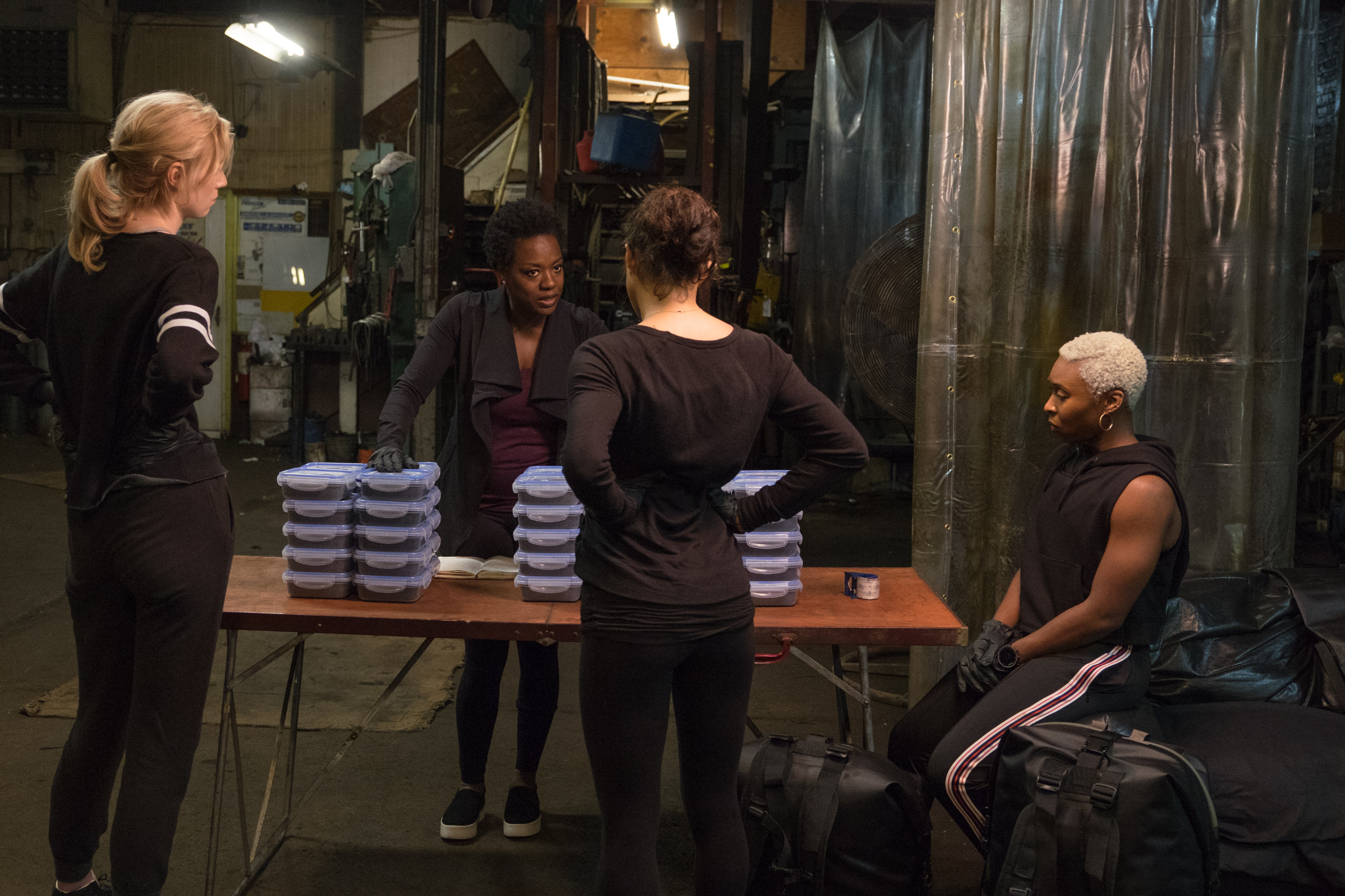 Elizabeth Debicki, Michelle Rodriguez, Viola Davis et Cynthia Erivo sont assises et debout ensemble dans un entrepôt à Widows.