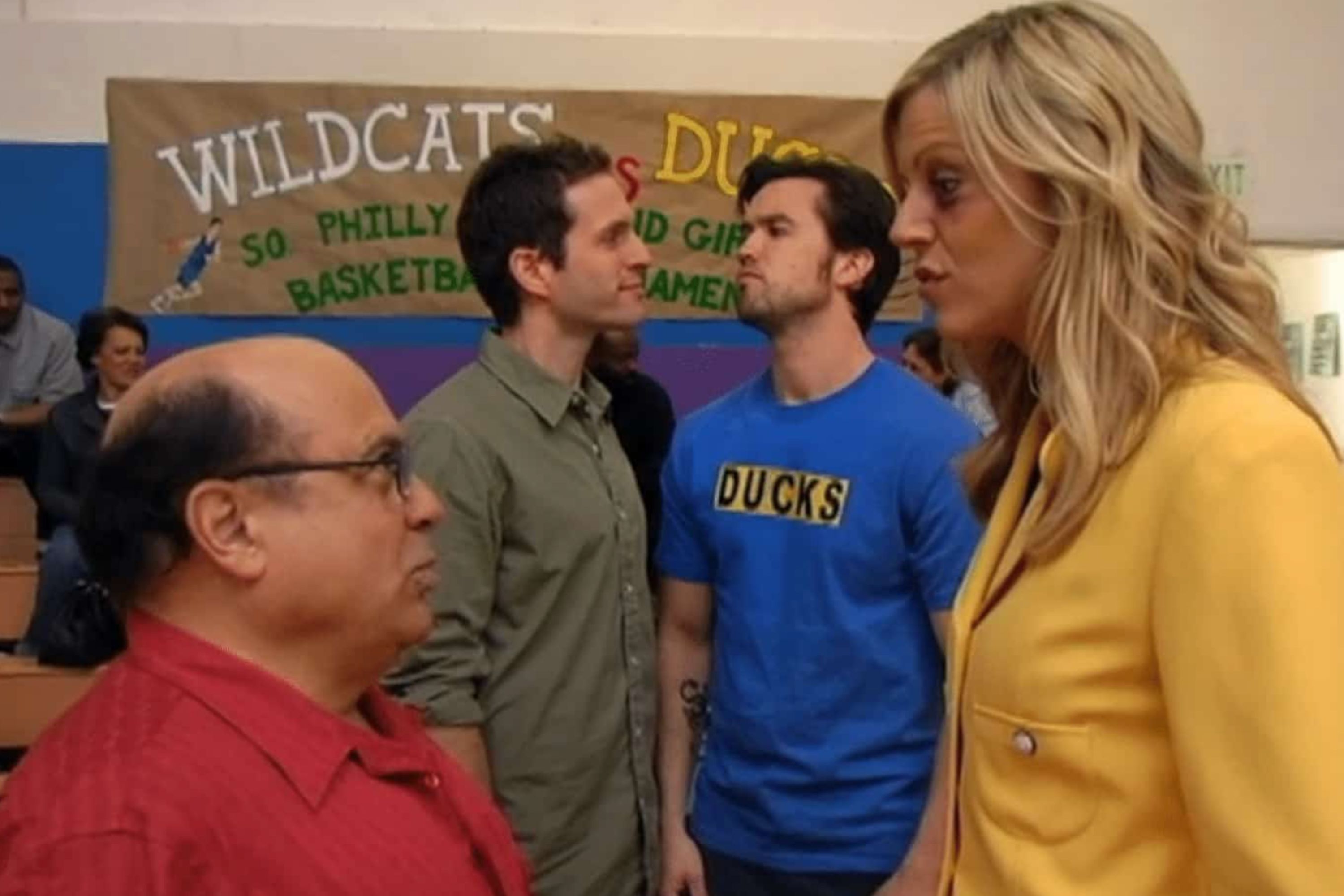 The gang facing off in front of a sign in The Gang Gives Back from It's Always Sunny in Philadelphia.