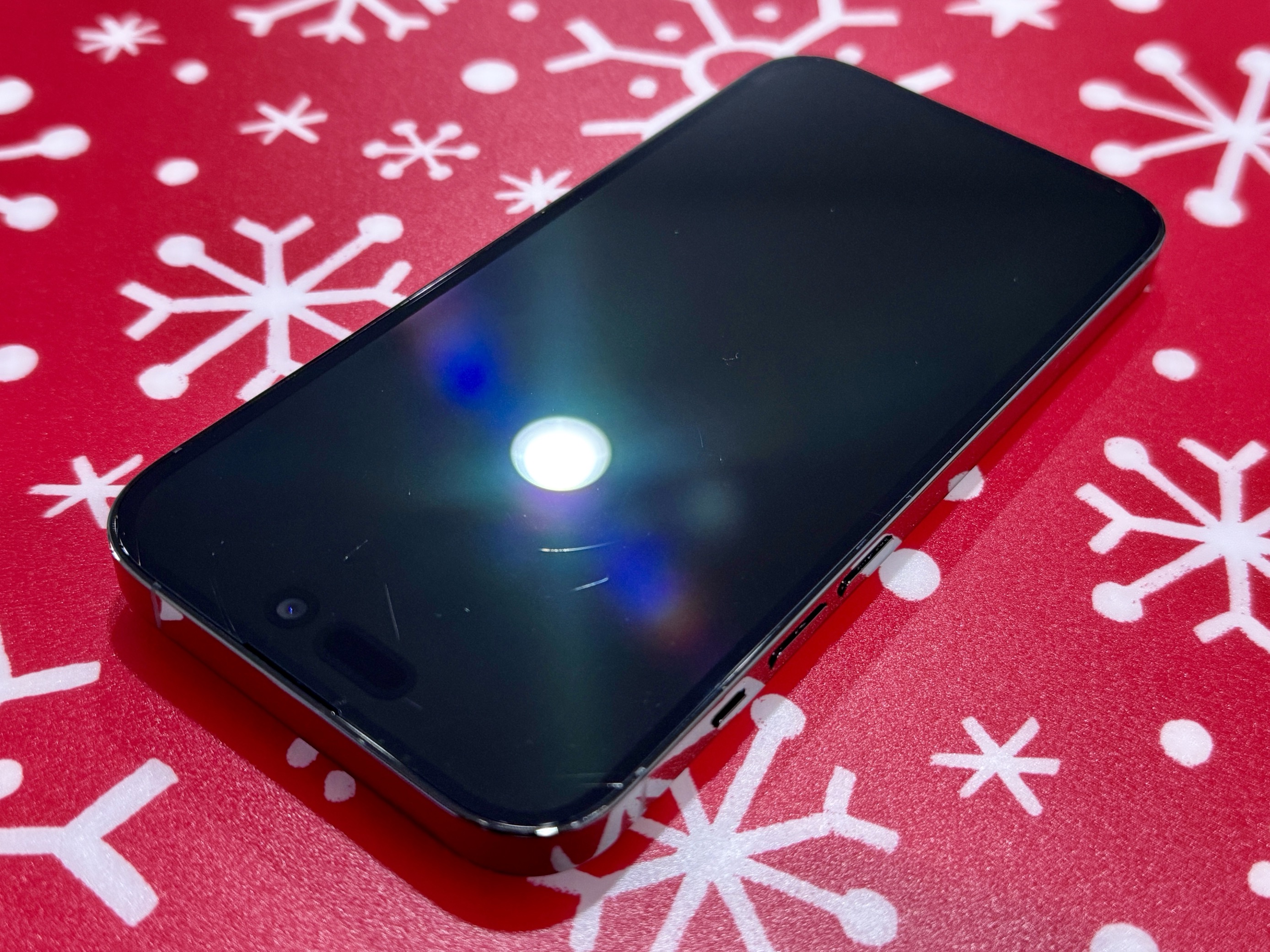 A picture of an iPhone 14 Pro, showing various scratches on its screen.