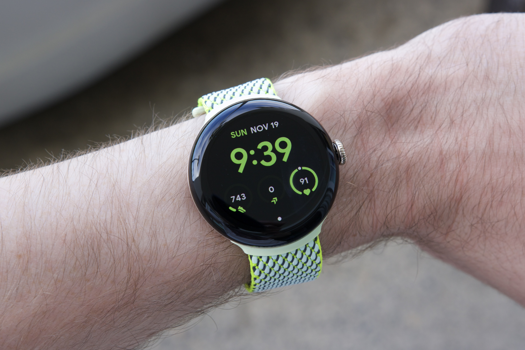 किसी ने पीले/हरे फैब्रिक बैंड वाली Google Pixel Watch 2 पहन रखी है।