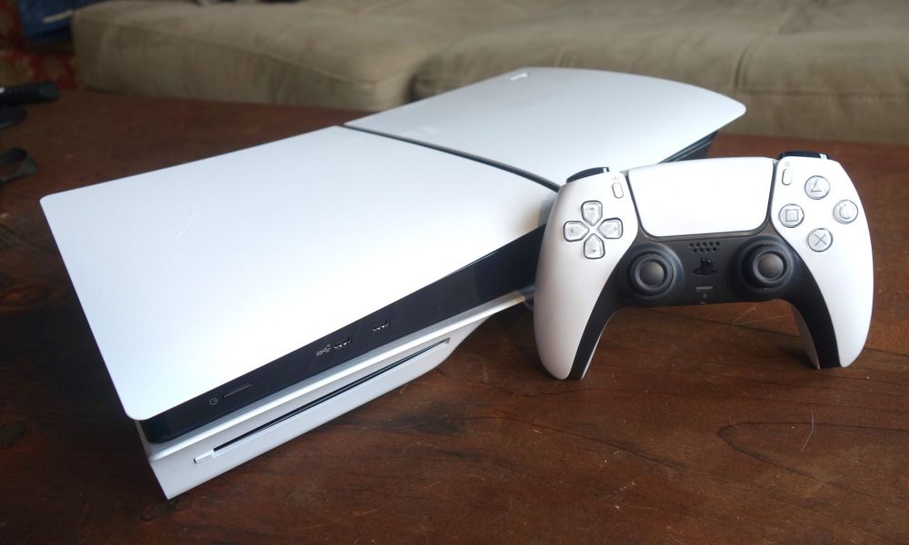 A PS5 sits on a table with a DualSense standing up next to it.